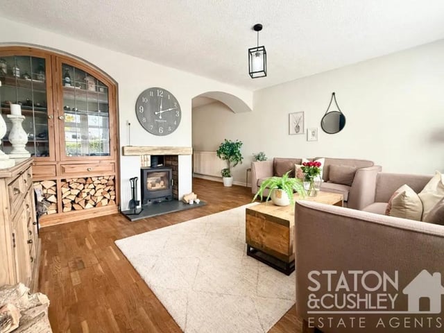 A spacious, beautifully presented room featuring a striking log burner that elegantly separates an additional flexible space, ideal for use as a dining area, home office, playroom, or snug.