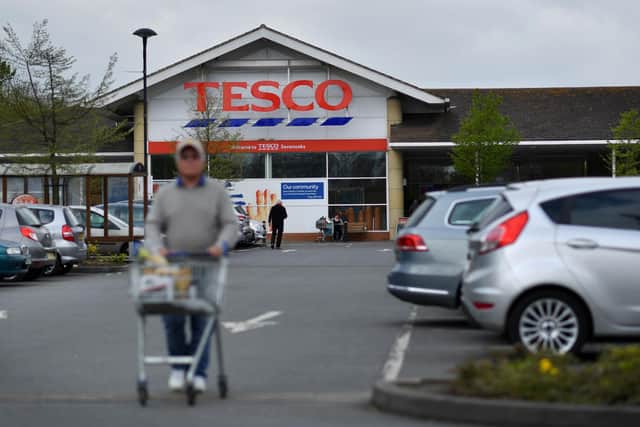 A customer pushes a shopping trolley as he walks through the car park of a Tesco  (Photo credit should read BEN STANSALL/AFP via Getty Images)