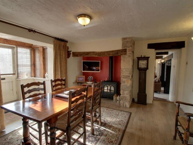 Providing the perfect space for family meals is this lovely dining room that is characterised by an Inglenook-style fireplace with gas-flame stove. The room opens into the front porch, which has windows set into an oak-framed surround and a door giving access to the front garden.