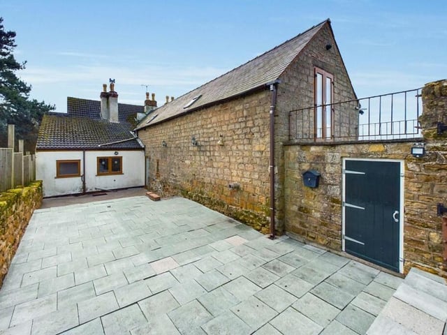This photo shows the balcony leading from the master bedroom at the £700,000 house and, beneath it, a characterful courtyard.