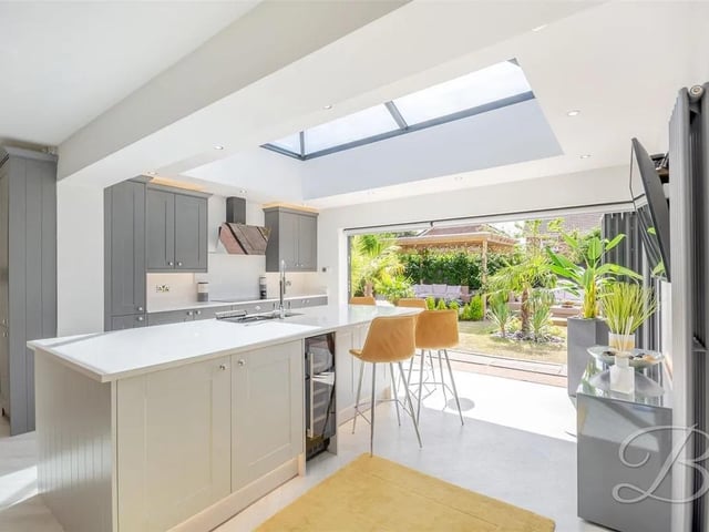 The open plan kitchen is fitted with a range of high-end cabinetry, integrated appliances, an inset sink, and a stunning feature island ideal for casual dining and entertaining. A large skylight and expansive bifolding doors fill the space with natural light.