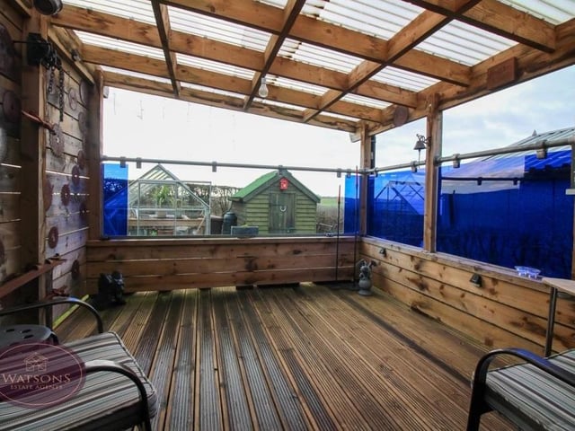 As well as the summer house, the garden includes this terrific, decked seating area. Timber-built., it is covered too.