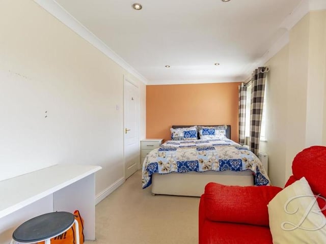 This bedroom is so lengthy and spacious that it has room for its own sofa. Windows offer plenty of natural light.