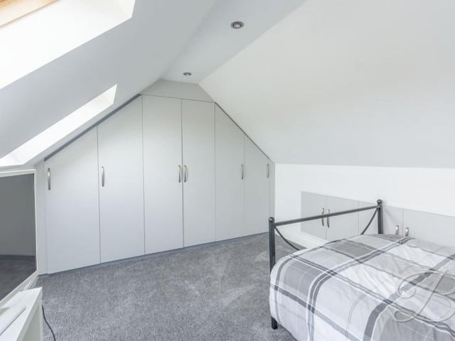 We're up to the second floor now, and this is the first of two bedrooms to inspect. It boasts a built-in wardrobe, a carpeted floor, space for a desk and two windows to the back of the house.
