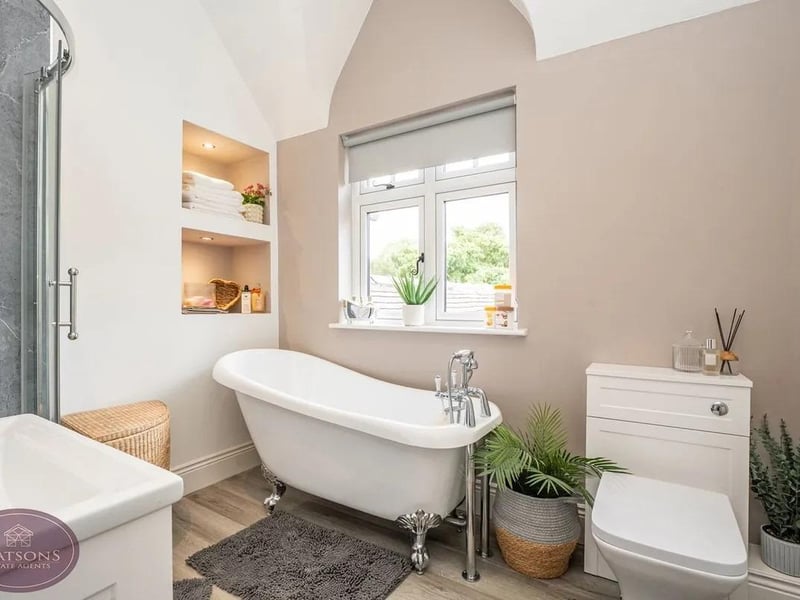 A stunning bathroom with freestanding rolltop bathtub with claw feet and a hand-held shower and corner shower cubicle with mains-fed rainfall effect shower. The perfect place to relax and unwind