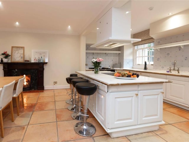 The contemporary country dining kitchen has a range of built storage options including a central breakfasting island, and a focal fireplace.
