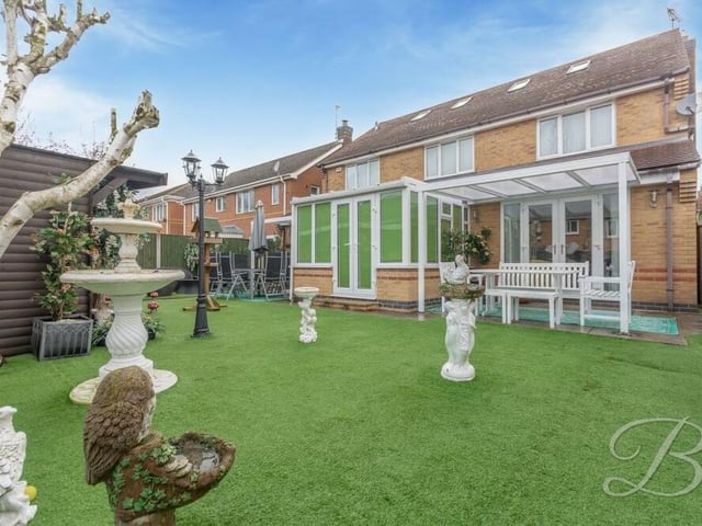 Moving outside now, here is the back garden, which features a low-maintenance, artificial lawn and covered seating area. You can also see the conservatory and its French doors leading outside.