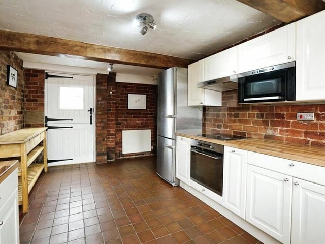 The kitchen is an alluring mix of contemporary, integrated appliances and exposed brickwork and ceiling beams. There is also an original stable door that leads to the garden.