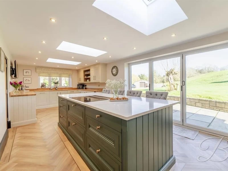 An outstanding, light-filled kitchen beautifully designed with high-end matching cabinetry and integrated appliances, creating a sleek and contemporary feel.