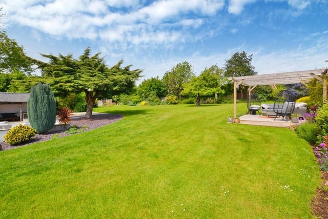 Stepping outside, let's take a look at a handful of exterior photos, starting with this large, formal lawned garden at the back of the house. It is totally enclosed with flower/shrub borders. You can also see decking with a seating area and pergola.