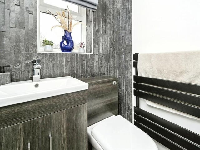 Next to the utility room is this downstairs toilet. It includes a WC, wash hand basin in vanity unit, and heated towel-rail.