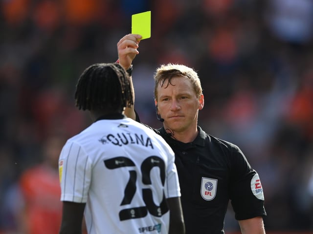 Referee John Busby issues a yellow card to Fulham player Domingos Quina.
