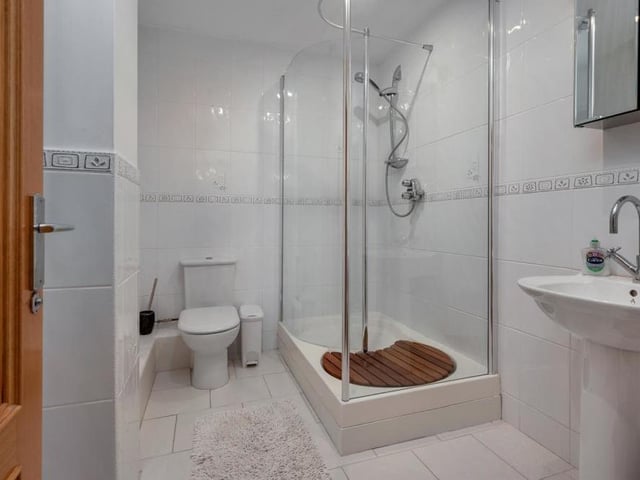 At one end of the gym is this shower room, which comprises a modern three-piece suite with chrome fittings. There is a large, tiled shower enclosure, a pedestal wash hand basin with mixer tap, low-flush WC, tiled floor, heated towel-rail and ceiling spotlights.