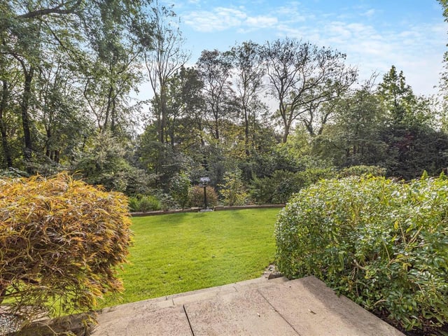 The garden is filled with mature trees, shrubs and plants, surrounding a central lawn..