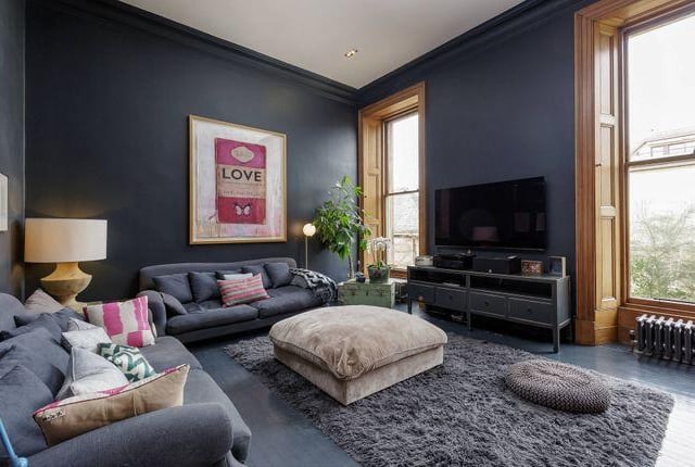 The livingroom with tasteful and homely dark walls and large windows.