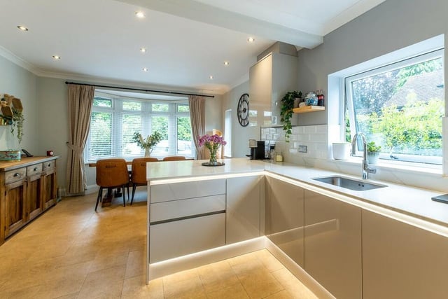 Our photo gallery opens in the stunning dining kitchen at the £795,000 Ravenshead property. It features a range of high-spec wall and base units, with quartz stone worktops. In the background, you can see a dining area in the shadow of a bay window