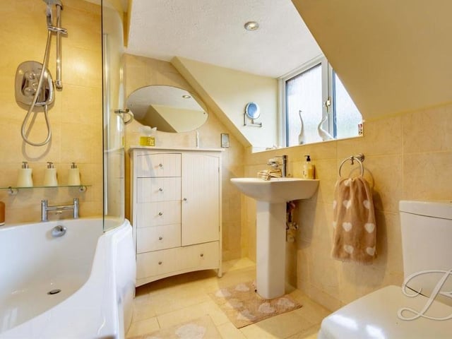 Here is the en suite bathroom that forms part of the master bedroom. The white suite comprises a panelled bath, with overhead shower, pedestal sink and a low-flush WC.