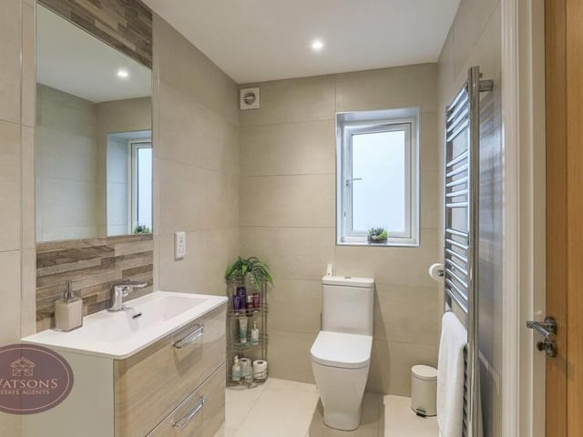 Here is the rest of the en suite to the master bedroom. It comprises a vanity sink unit, WC, chrome, heated towel-rail, ceiling spotlights, fully tiled walls and a porcelain tiled floor with underfloor heating.
