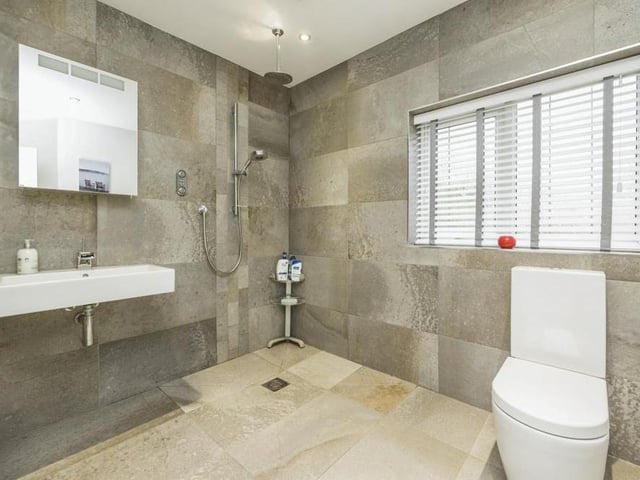 The stylish en suite wet room to the first bedroom is fully tiled with a rainfall shower and hand shower. It also includes a vanity wash hand basin with mixer tap, low-level WC, two towel radiators and an extractor fan.