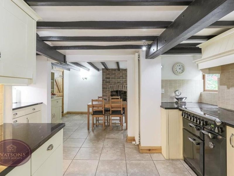 Integrated appliances within the dining kitchen include a fridge and dishwasher, while there is space for a Range-style cooker with extractor over. In the background, you can probably spot a brick-built fireplace with inset multi-fuel burner.