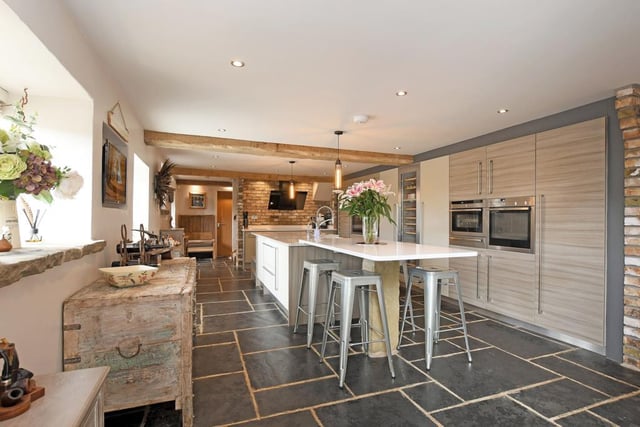 The kitchen has a large central island with a granite work surface, a Neff oven, a full-height wine cooler and several other integrated appliances, such as a fridge tucked away under the counter.
