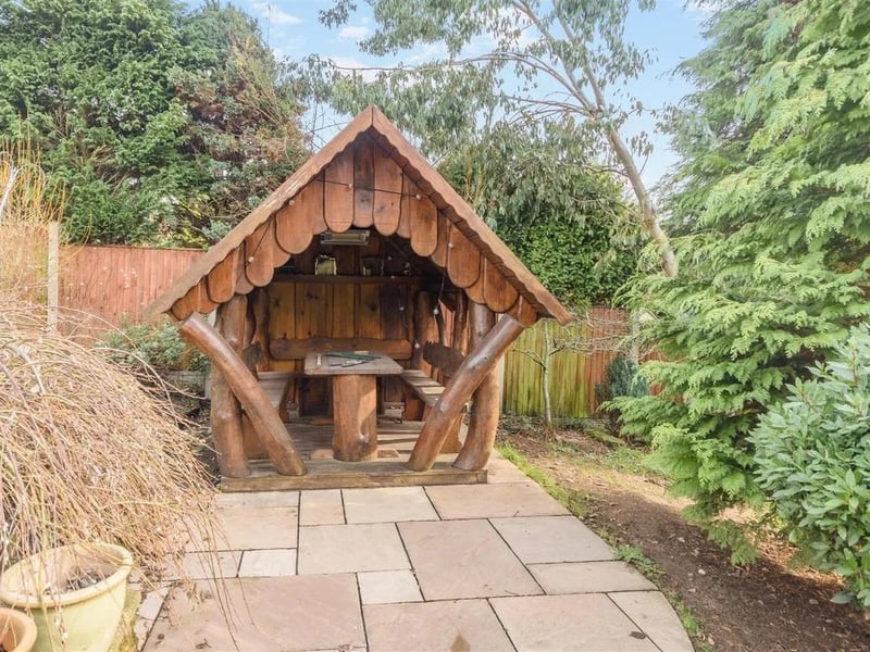 Central steps from the main patio leads down to a further sandstone patio area leading to a central winding pathway leading to the feature hobbit house with lighting and a heater.