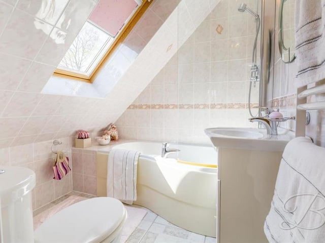 The second bedroom also benefits from attractive en suite facilities. A fully tiled suite consists of a panelled bath, chrome overhead shower, low-flush WC and heated towel-rail.
