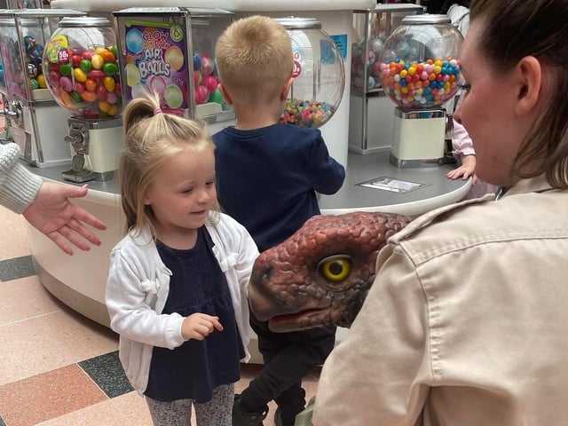 A brave young visitor says hello to a little dinosaur.