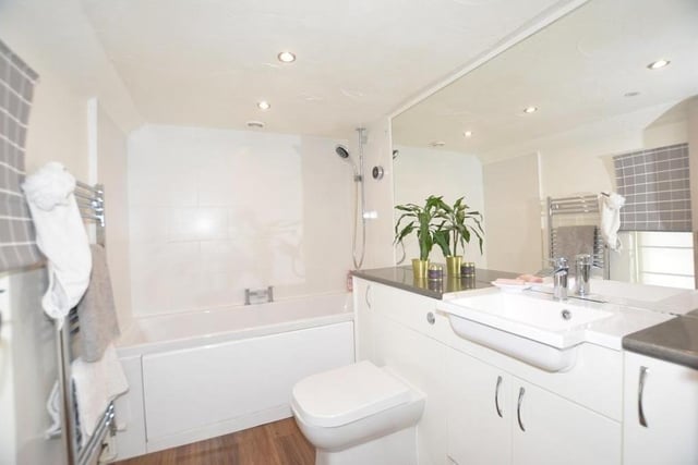 Before we move on to the bedrooms, let's take a look at the family bathroom on the first floor. There is a panelled bath with shower over, a low-level WC, a wash hand basin with vanity storage and a heated towel-rail.