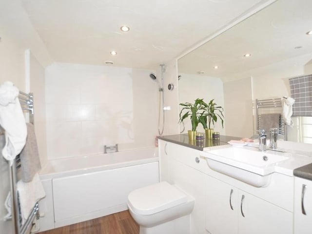 Before we move on to the bedrooms, let's take a look at the family bathroom on the first floor. There is a panelled bath with shower over, a low-level WC, a wash hand basin with vanity storage and a heated towel-rail.