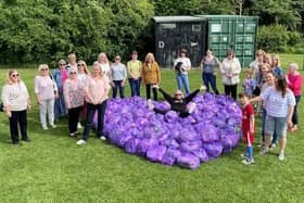 Members of a Slimming World group pose with a purple heart made from the clothes they have donated as part of the Big Slimming World Clothes Throw 2022.