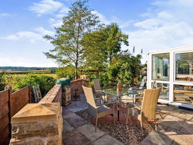 The back garden includes this paved patio area for seating, with access from the conservatory. It boasts tiered sections and steps leading to a lawn with mature trees, shrubs and bushes. Just look at the spectacular views.