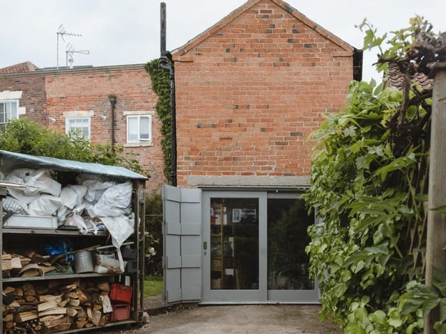 The former barn doors of the cottage have been replaced by double-glazed, hardwood-framed sliding doors, flooding the space with light. Here you can also see a wood store and bike shed.