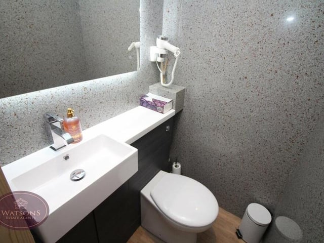 A look at the toilet within the bungalow's annexe. It consists of a concealed-cistern WC, hand basin and wall-mounted mirror with LED lighting.