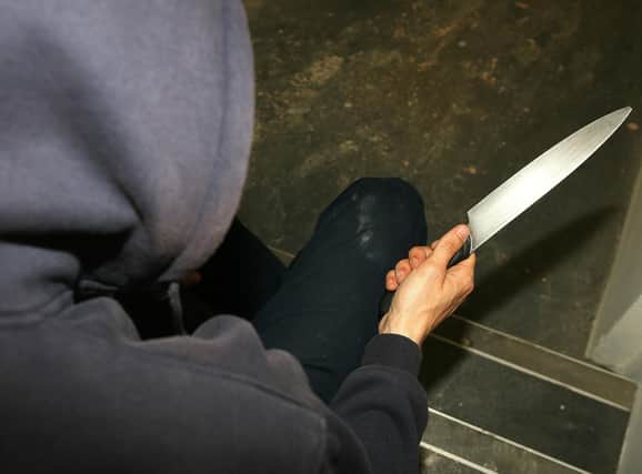PICTURE POSED BY MODEL. A general view of a man in a hoodie holding a knife.