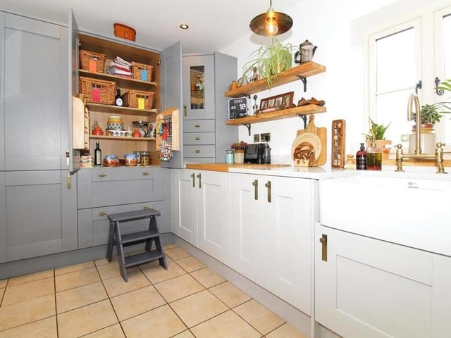 The kitchen is littered with integrated appliances, and also features oak shelving, Silestone and oak worktops and a Belfast sink with a brushed brass mixer tap.