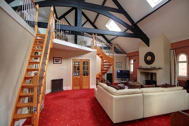 Measuring at a huge 6.71m x 6.30m, the property's living room includes a feature fireplace with solid fuel burner, two staircases to mezzanine areas and  a stained glass feature window.