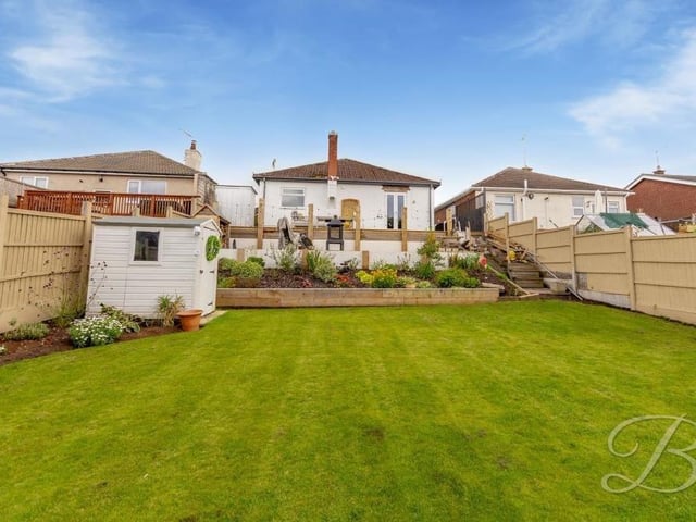 This is the view of the back of the £225,000-plus bungalow from the summer house at the far end of the lawn.