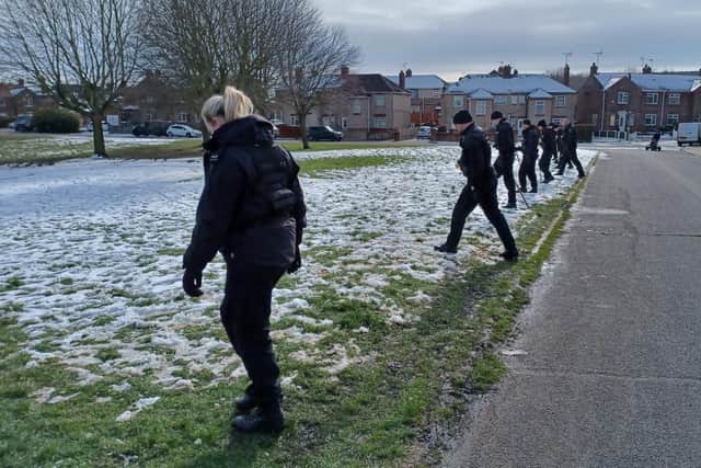 Police officers search the scene.
