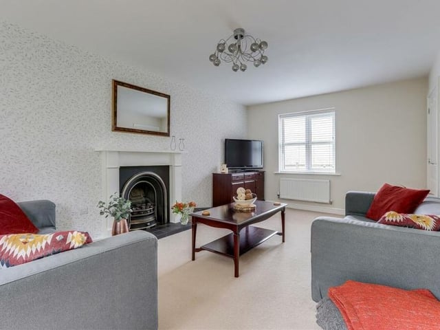 Adding character to the living room is a recessed open decorative fireplace and surround. Other features include a window facing the front of the property, a carpeted floor and a TV point.