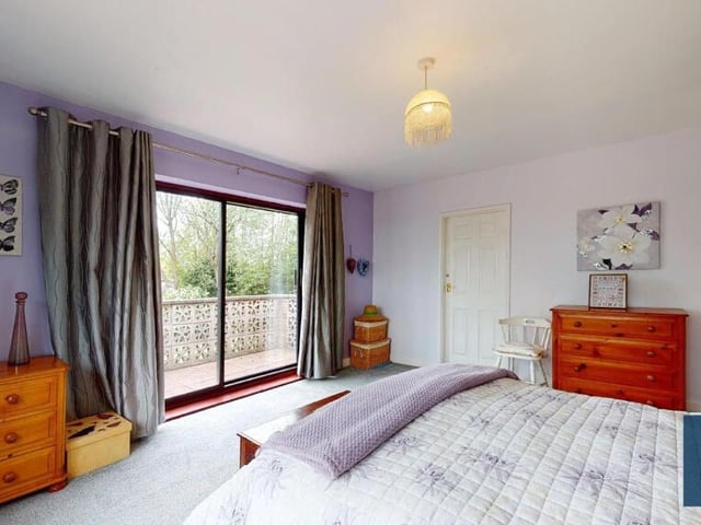 Here is the striking main bedroom, which includes double-glazed sliding patio doors that open out to the side garden. A range of fitted wardrobes is complemented by over-bedhead storage cupboards.