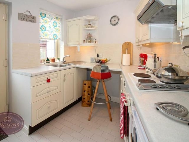 Our first interior photo of the annexe shows the compact but stylish kitchen, which includes a range of matching wall and base units, with work surfaces incorporating a sink and drainer unit.