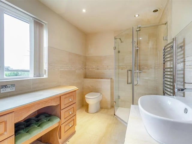A contemporary three piece suite with chrome fittings comprising a corner tiled shower enclosure. Purpose built fitted stand with inset wash hand basin with mixer tap and storage shelf beneath. Low flush WC with enclosed cistern. Attractive tiling to the walls, tiled floor, electric underfloor heating, ceiling spotlights, extractor fan and chrome heated towel rail. There are ample fitted wardrobes with hanging rails and shelving, plus a fitted dressing table with double power point.
