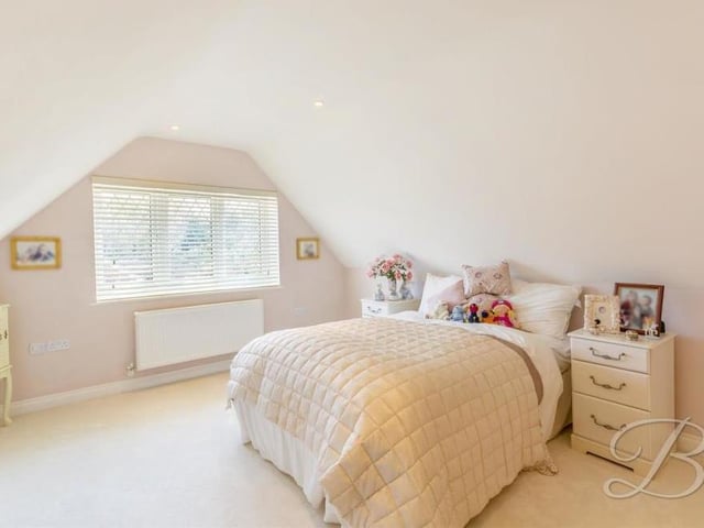 All six upstairs bedrooms are decorated in neutral colours, including this, the second one. Overlooking the front of the house, it has a carpeted floor and downlights. There is also a fitted wardrobe with hanging rails and drawers.