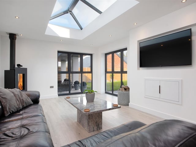 The living area has a log burner with quartz base, and two sets of floor-to-ceiling windows lead out onto the rear garden.