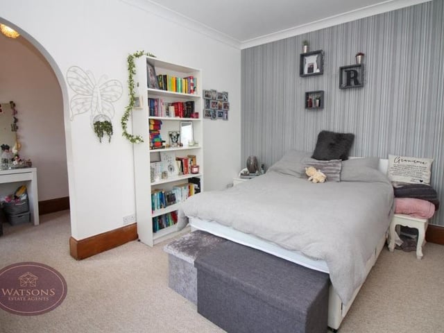This bedroom has just about everything! A range of fitted wardrobes, and an open archway leading to a dressing area.