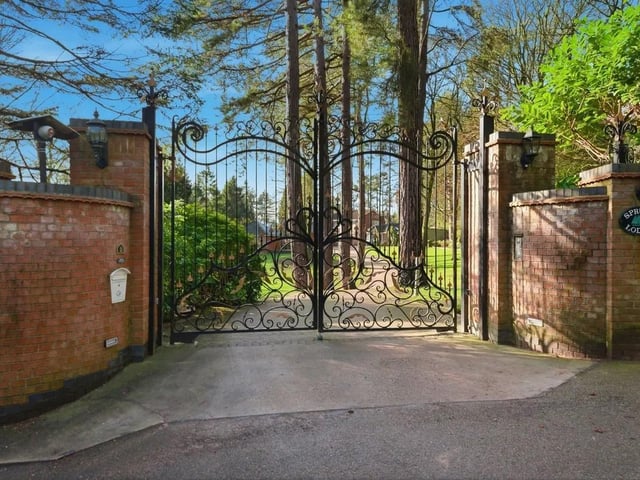 From the moment the wrought iron gates open, the approach sets the tone. A sweeping, tree-lined driveway winds through manicured lawns and mature planting, creating a true sense of arrival before the house even comes into view.