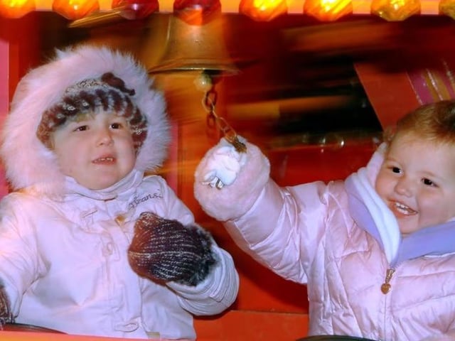 Four-year-old Lucy Hitchcock and one-year-old Aimee Brudzinska from Mansfield take turns ringing the bell on a fairground ride at the 2006 Portland College bonfire display