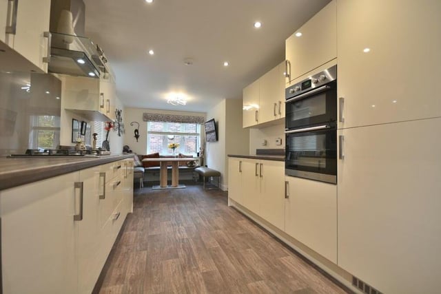 This image shows the integrated, contemporary double oven in the kitchen, which also benefits from eight LED ceiling spotlights and a vinyl floor. At the far end is the dining area.