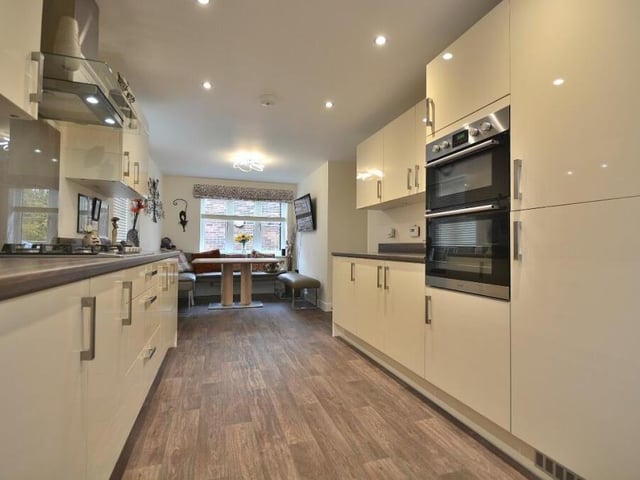 This image shows the integrated, contemporary double oven in the kitchen, which also benefits from eight LED ceiling spotlights and a vinyl floor. At the far end is the dining area.